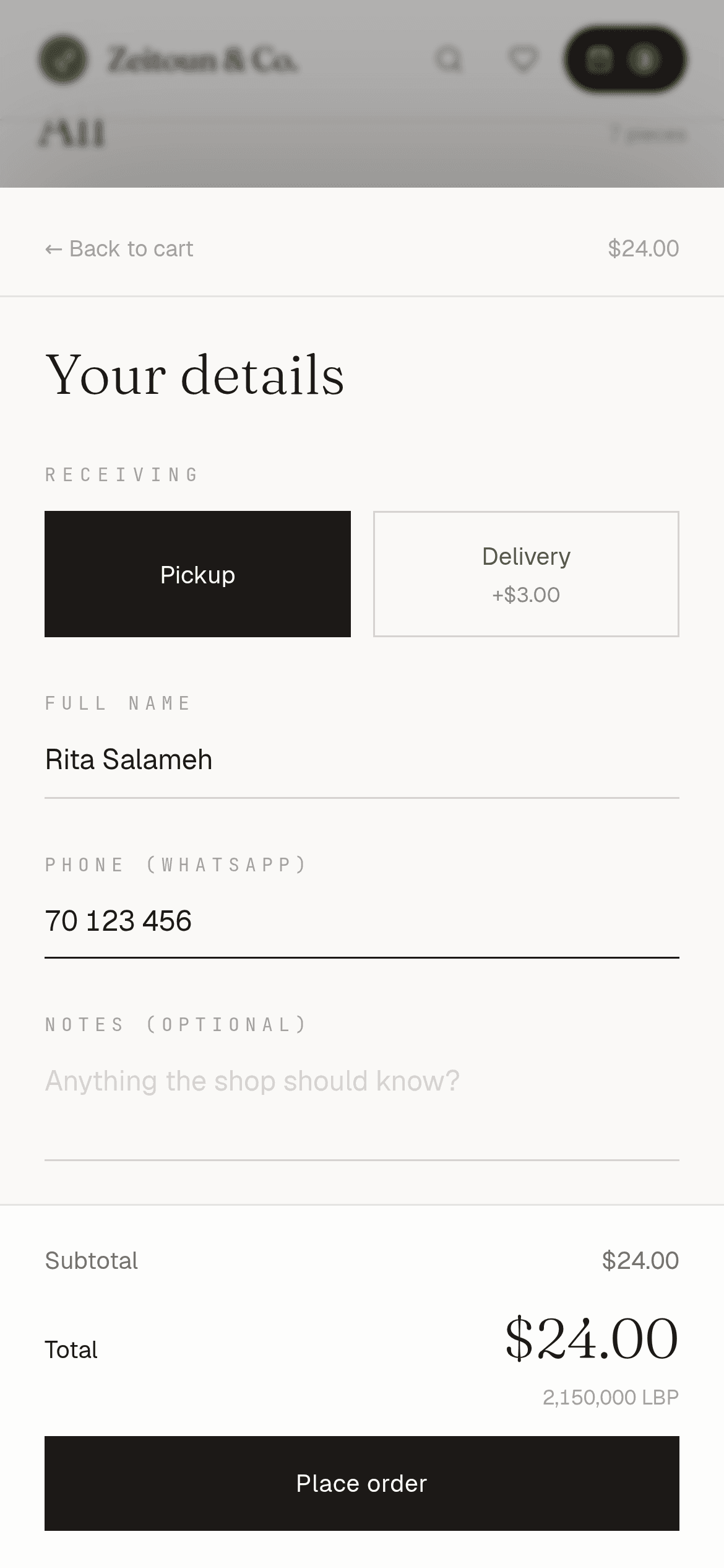 Table online store checkout on a phone for the Zeitoun & Co. demo pantry shop: Pickup chosen over Delivery (+$3.00), the customer's name and WhatsApp number filled in, and a $24.00 total with 2,150,000 LBP above the Place order button