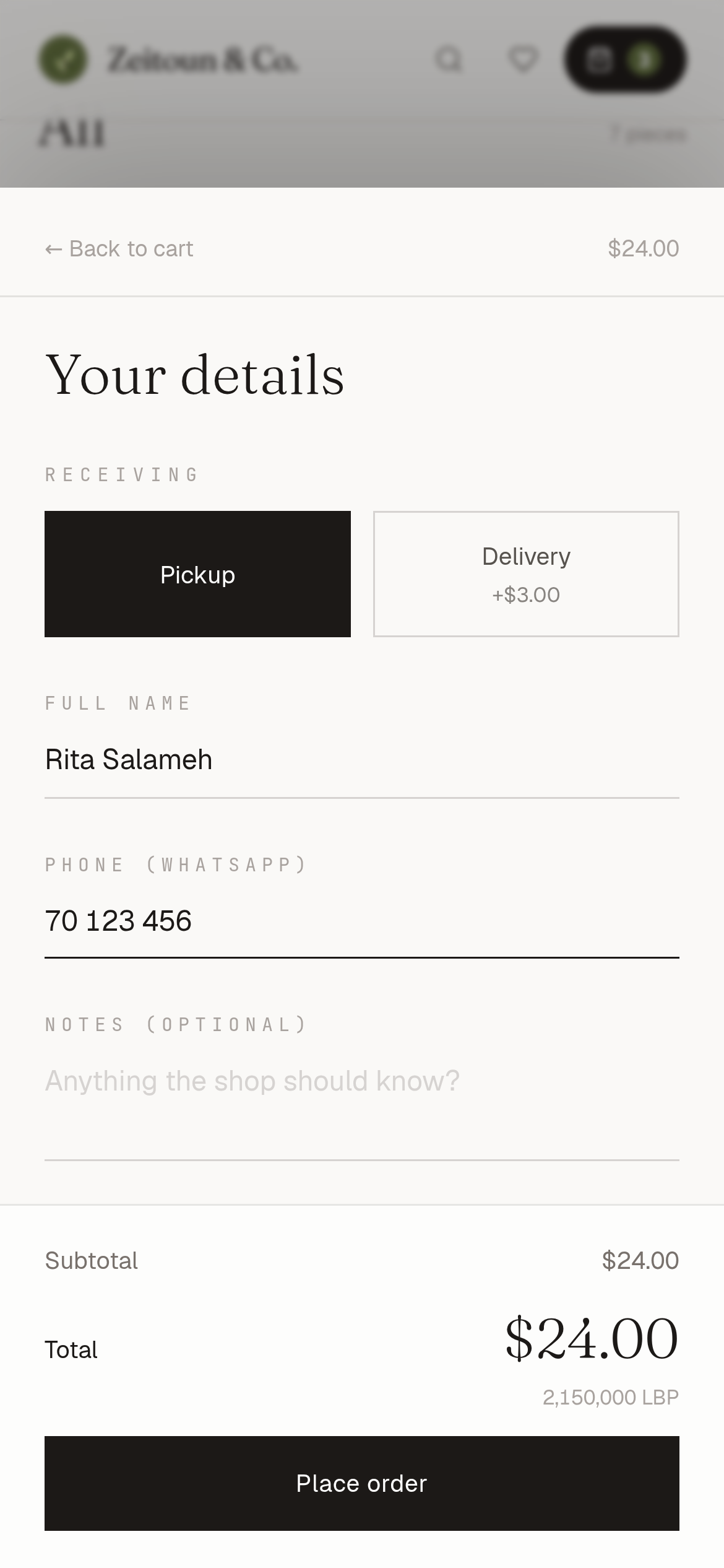 Table online store checkout on a phone for the Zeitoun & Co. demo pantry shop: Pickup chosen over Delivery (+$3.00), the customer's name and WhatsApp number filled in, and a $24.00 total with 2,150,000 LBP above the Place order button